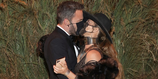 Ben Affleck and Jennifer Lopez are seen sharing a kiss through their masks at the Met Gala.