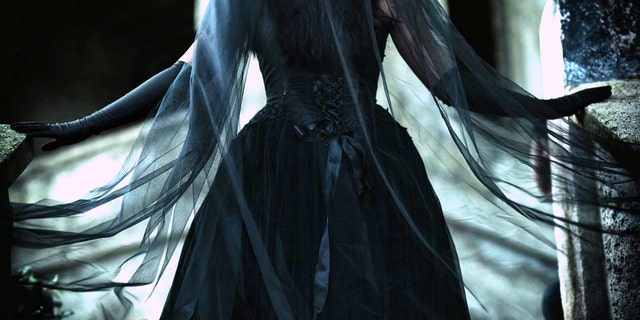 A black wedding gown, in Victorian style, with a long, black flowing veil.  The mourning veil is sometimes thought of as a shield to hide grief.