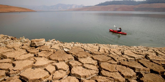 A kayaker fishes in Lake Oroville as water levels remain low due to continuing drought conditions in Oroville, Calif., Sunday, Aug. 22, 2021. 