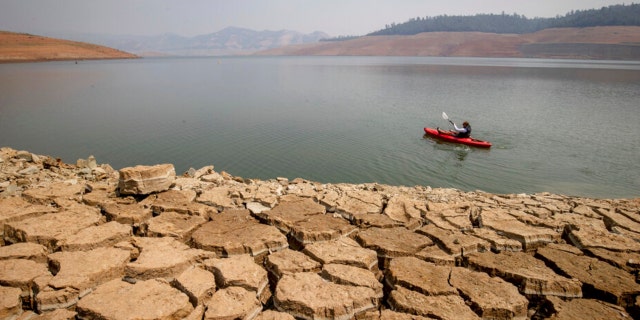 A kayaker fishes in Lake Oroville as water levels remain low due to continuing drought conditions in Oroville, Calif., Sunday, Aug. 22, 2021.