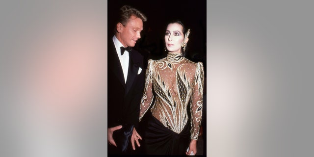 El diseñador Bob Mackin և Singer և Actriz Cher asiste a la Gala del Costume Institute Metropolitan Museum of Art, Nueva York, Nueva York, 1985.
