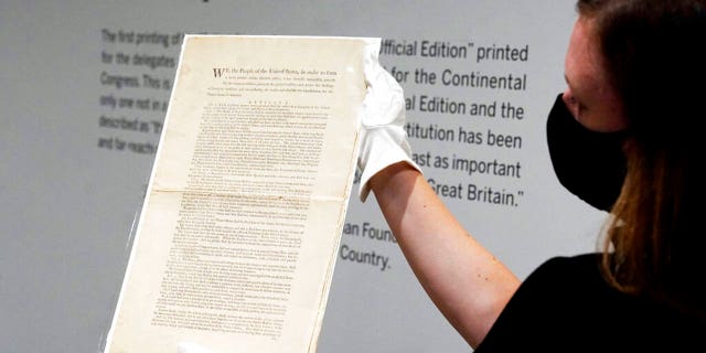 Ella Hall, a specialist in Books and Manuscripts at Sotheby's, in New York, holds a 1787 printed copy of the U.S. Constitution. (AP Photo/Richard Drew)