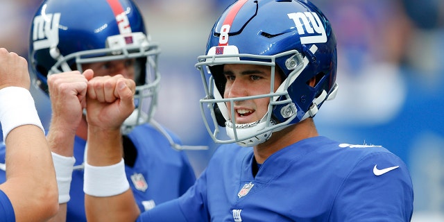 New York Giants quarterback Daniel Jones, right, talks to teammates before an NFL preseason football game against the New England Patriots Sunday, Aug. 29, 2021, in East Rutherford, N.J. (AP Photo/Noah K. Murray)