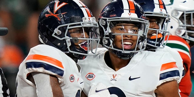 Virginia wide receiver Ra'Shaun Henry (2) congratulates wide receiver Dontayvion Wicks after Wicks scored a touchdown in the second half of an NCAA college football game against Miami on Thursday, September 30, 2021, in Miami Gardens, Florida.