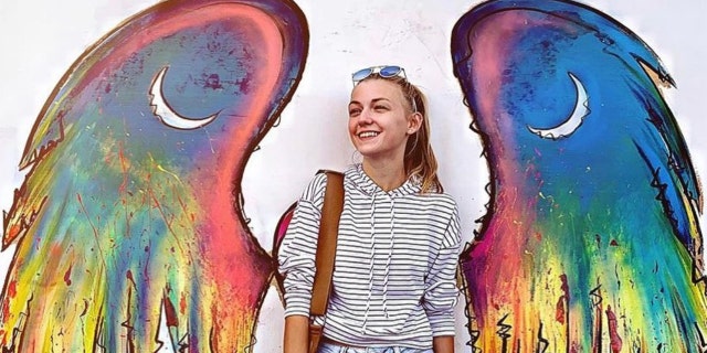 Gabby Petito poses in front of a winged mural