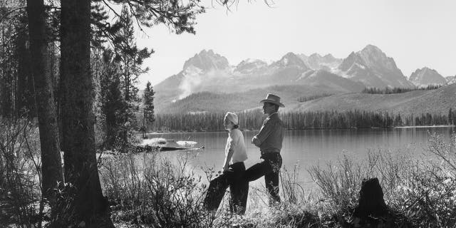 American actor Gary Cooper and his wife "Rocky" pose beside the Red Fish Lake in Idaho, circa 1940.