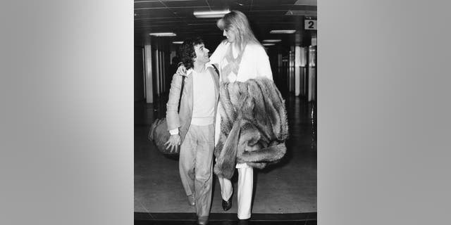 Comedian and actor Dudley Moore with his arm around then-girlfriend Susan Anton, arriving at Heathrow Airport, London, October 1st 1980. 