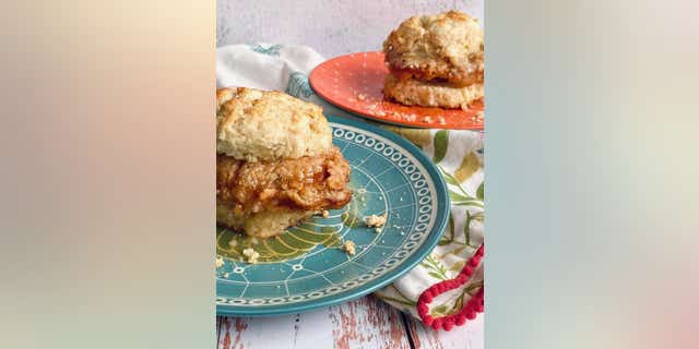Each buttermilk biscuit slice can receive a dollop of fresh honey butter before the chicken is placed in between.