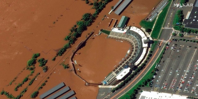 In a satellite image provided by Maxar Technologies, the stadium for the Somerset Patriots Double-A baseball team is partially flooded by overflow from the Raritan River on Thursday, Sept. 2, 2021, in Bridgewater Township, N.J., the day after torrential rain from the remnants of Hurricane Ida drenched the area. A railroad line to the left of the stadium is submerged. 
