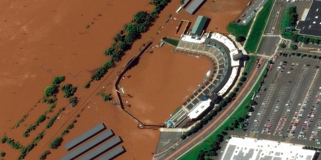 In a satellite image provided by Maxar Technologies, the stadium for the Somerset Patriots Double-A baseball team is partially flooded by overflow from the Raritan River on Thursday, Sept. 2, 2021, in Bridgewater Township, N.J., the day after torrential rain from the remnants of Hurricane Ida drenched the area. A railroad line to the left of the stadium is submerged. 