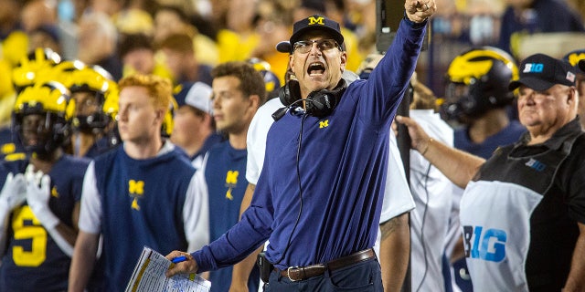 Michigan coach Jim Harbaugh signals a Michigan first down on the sideline during the fourth quarter of the team's NCAA college football game against Washington in Ann Arbor, Ek., Saterdag, Sept.. 11, 2021.