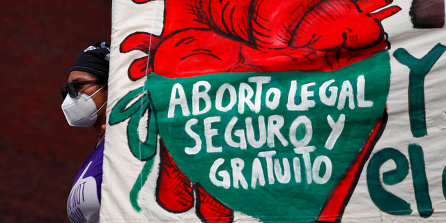 A woman holds a banner reading, in Spanish, "Legal, safe, and free abortion, legalize and decriminalize abortion now, for the independence and autonomy of our bodies," as abortion-rights protesters demonstrate in front of the National Congress in Mexico City.