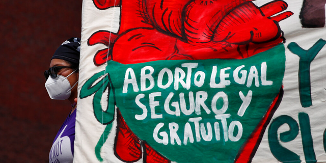 A woman holds a banner reading, in Spanish, "Legal, safe, and free abortion, legalize and decriminalize abortion now, for the independence and autonomy of our bodies," as abortion-rights protesters demonstrate in front of the National Congress in Mexico City.