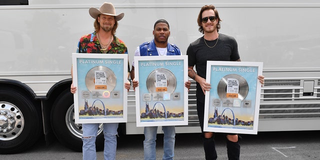 Brian Kelley and Tyler Hubbard of Florida Georgia Line and Nelly, center, take photos with their Platinum Single for ‘LilBit’ during CMT Crossroads: Nelly &amp; Friends at The Factory At Franklin on September 01, 2021 in Franklin, Tenn. 