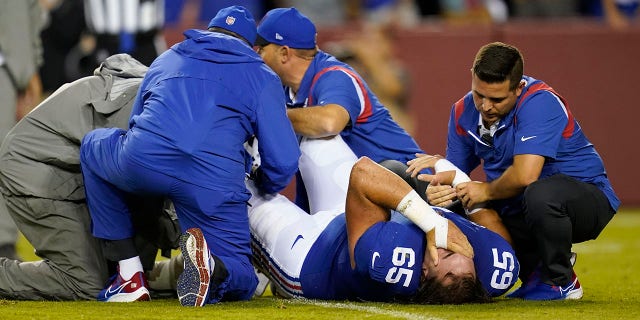 Los miembros del personal médico de los New York Giants tienden a centrar a Nick Gates durante el juego del equipo de fútbol de Washington el 16 de septiembre de 2021 en Landover, Maryland.