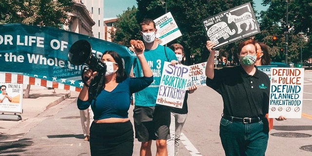 Pro-life Democrats protest at the DNC in 2020. Terrisa Bukovinac shouts in a microphone with Matt Tuman, board chair of Democrats for Life of America, marching behind her and Herb Geraghty, executive director of Rehumanize International, at the right.