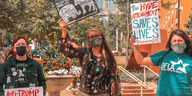 Herb Geraghty, executive director of Rehumanize International, protests with Maria Oswalt and Kirsten Vail, liberal pro-life activists. (Photo credit: Terrisa Bukovinac)