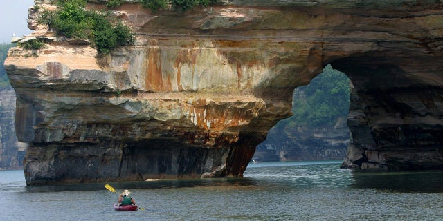 This Aug. 2, 2003 photo shows a kayaker in Lake Superior off the cliffs at Pictured Rocks National Lakeshore near Munising, Mich.
