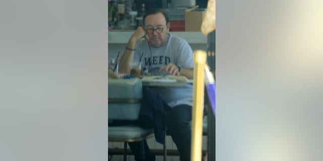 Spacey was seen reading from a book as he sat alone eating his lunch.