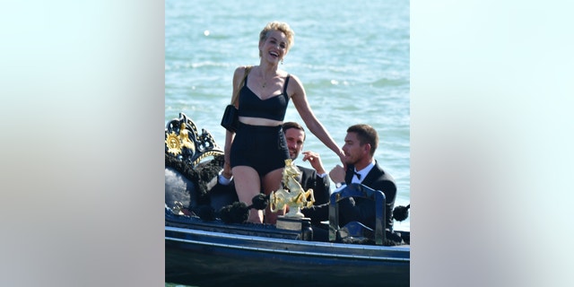 63-year old American Actress Sharon Stone looks stunning in her tight black outfit while out on a boat with two male models in Venice. The ‘Basic Instinct’ star showed off her legs during her glamorous shoot for the fashion brand Dolce and Gabbana.