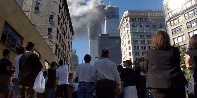 Pedestrians in lower Manhattan watch smoke billow from New York's World Trade Center on Tuesday, 9/11/01.