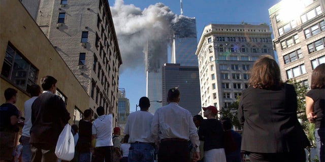 Pedestrians in lower Manhattan watch smoke billow from New York's World Trade Center on Tuesday, 9/11/01.