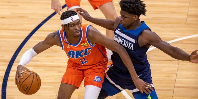 Oklahoma City Thunder guard Shai Gilgeous-Alexander ( 2 ) dribbles the ball as Minnesota Timberwolves forward Anthony Edwards ( 1 ) plays defense in the second half at Target Center.
