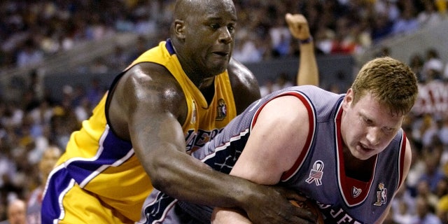 Los Angeles Lakers' Shaquille O'Neal (L) reaches from behind to latch onto the ball and New Jersey Nets' Todd MacCulloch during Game 1 of the NBA Finals June 5, 2002 in Los Angeles.