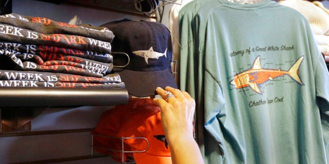 In this July 2, 2014 photo, a customer examines shark-themed clothing at a store in Chatham, Massachusetts. 
