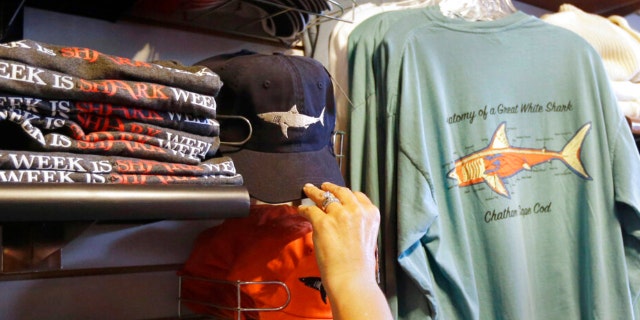 In this July 2, 2014 photo, a customer examines shark-themed clothing at a store in Chatham, Massachusetts.