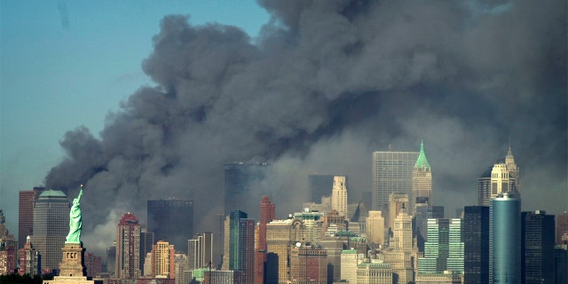 Thick smoke billows into the sky from the area behind the Statue of Liberty, lower left, where the World Trade Center was, on Tuesday, Sept. 11, 2001.