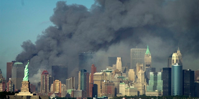 Thick smoke billows into the sky from the area behind the Statue of Liberty, lower left, where the World Trade Center was, on Sept. 11, 2001.