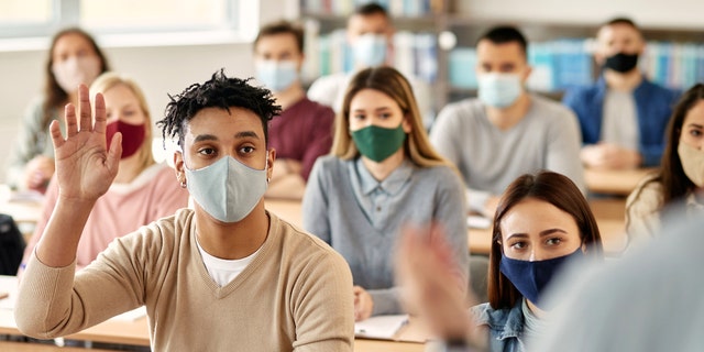 College students in class, wearing masks. Said William Bennett of the new student loan handout plan, "It's favoring people who have gone to college or graduate school … [And] there's a bit of a ruse here."