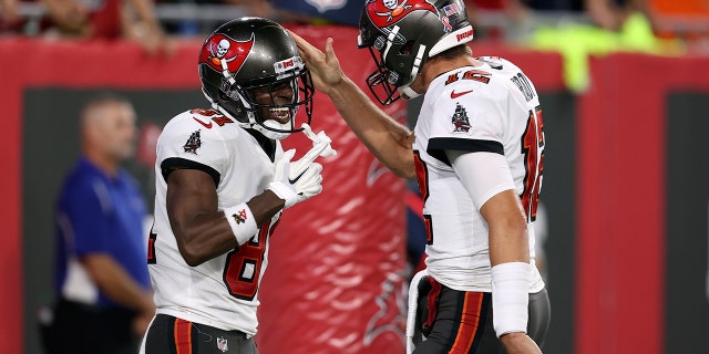 Tampa Bay Buccaneers quarterback Tom Brady (12) celebrates with wide receiver Antonio Brown (81) after Brown caught a touchdown pass against the Dallas Cowboys during the first half of an NFL football game Thursday, Sept. 9, 2021, in Tampa, Florida.