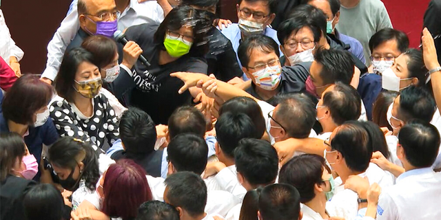 In this image taken from video by Taiwan's EBC, Premier Su Tseng-chang, in purple mask, tries to make a policy speech amid a scuffle between opposition Nationalist party and ruling Democratic Progressive Party lawmakersduring a parliament session in Taipei, Taiwan, Tuesday, Sept. 28, 2021. Taiwan's legislature on Tuesday descended into a rowdy brawl on Tuesday, after opposition lawmakers interrupted an important policy address and rushed the podium. (EBC via AP )