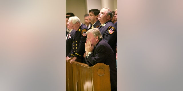 Then-Fire Commissioner Thomas Von Essen kneels at a memorial service for Firefighter Gregory Saucedo of Ladder Co. 5, a victim of the World Trade Center disaster, at Mary Queen of Heaven Catholic Church in Brooklyn.