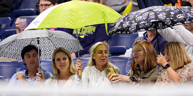 Fans cover themselves in the rain at Louis Armstrong Stadium during a match between Kevin Anderson of South Africa and Diego Schwartzman of Argentina in the second round of the US Open tennis championships on Wednesday 1st September 2021, in New York.  (AP Photo / Frank Franklin II)