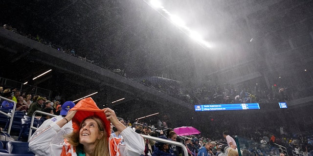 A fan covers himself in the rain at Louis Armstrong Stadium during a match between Kevin Anderson of South Africa and Diego Schwartzman of Argentina in the second round of the US Open tennis championships on Wednesday 1st September 2021, in New York.  (AP Photo / Frank Franklin II)