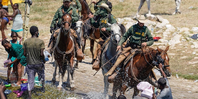 U.S. Customs and Border Protection mounted officers attempt to contain migrants as they cross the Rio Grande from Ciudad Acuña, Mexico, into Del Rio, Texas, Sunday, Sept. 19, 2021.