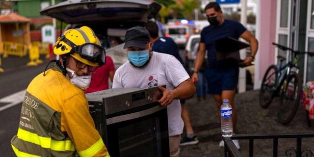 Les résidents retirent leurs effets personnels de leurs maisons alors que la lave s'écoule d'un volcan en éruption, alors qu'ils sont évacués de leur village de Los Llanos, sur l'île de La Palma dans les îles Canaries, en Espagne, le mercredi 22 septembre 2021.