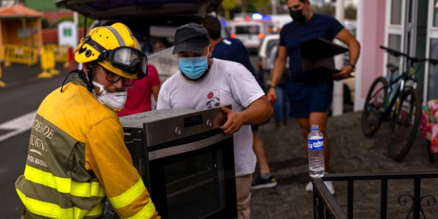 Les résidents retirent leurs effets personnels de leurs maisons alors que la lave s'écoule d'un volcan en éruption, alors qu'ils sont évacués de leur village de Los Llanos, sur l'île de La Palma aux îles Canaries, en Espagne, le mercredi 22 septembre 2021.