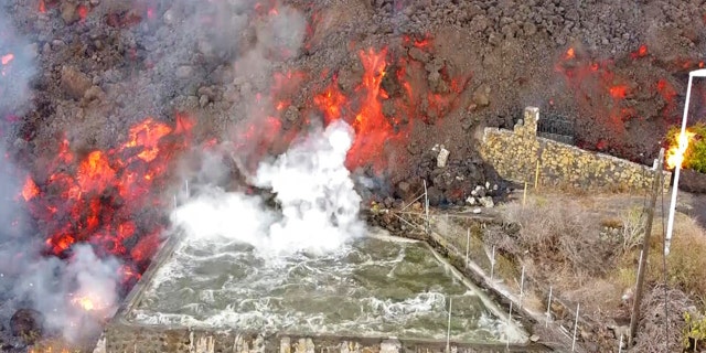 Hot lava reaches a balsa normally used for for irrigation after an eruption of a volcano on the island of La Palma in the Canaries, スペイン, Monday Sept. 20, 2021.