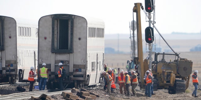 Workers examine a train car, Monday, Sept. 27, 2021, from an Amtrak train that derailed Saturday, near Joplin, Mont.