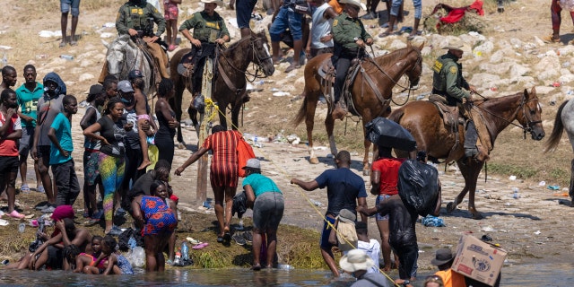 CIUDAD ACUNA, MÉXICO - 20 DE SEPTIEMBRE: Agentes montados de la Patrulla Fronteriza de los Estados Unidos ayudan a los inmigrantes haitianos en la orilla del Río Grande en Del Rio, Texas, el 20 de septiembre de 2021, visto desde Ciudad Acuña, México.  Cuando las autoridades de inmigración estadounidenses comenzaron a deportar a migrantes de Del Río de regreso a Haití, miles más esperaban en un campamento debajo de un puente internacional en Del Río, mientras que otros cruzaron el río de regreso a México para evitar la deportación.  (Foto de John Moore / Getty Images) 