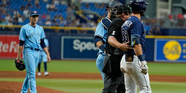 Tampa Bay Rays' Kevin Kiermaier, right, is held back by home plate umpire Bruce Dreckman and Toronto Blue Jays catcher Danny Jansen after Kiermaier was hit with a pitch by starting pitcher Ryan Borucki, 권리, during the eighth inning of a baseball game Wednesday, 씨족. 22, 2021, in St. Petersburg, Fla.