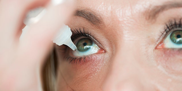 Woman using pipette ... applying eye drops