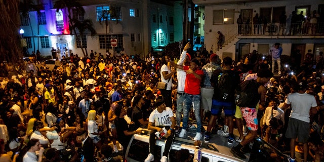 FILE - In this Sunday, March 21, 2021, file photo, crowds defiantly gather in the street while a speaker blasts music an hour past curfew in Miami Beach, Fla. (Daniel A. Varela/Miami Herald via AP, File)