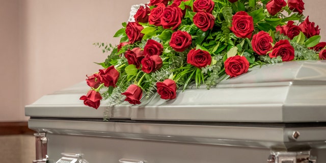 Roses sit on top of a closed casket at a funeral home.