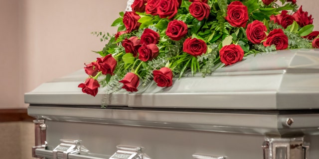 Roses sit on top of a closed casket at a funeral home.