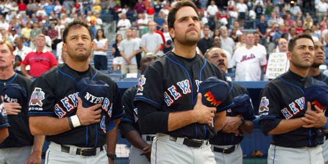 Left fielder Joe McEwing #47, shortstop John Valentin #4, catcher Mike Piazza #31, third baseman Edgardo Alfonzo #13 and right fielder Jeromy Burnitz #20 of the New York Mets hold their FDNY and NYPD hats over their hearts during the national anthem before the second game of a MLB double-header against the Atlanta Braves on September 11, 2002 at Turner Field in Atlanta, Georgia.  The Mets shut out the Braves 5-0. 